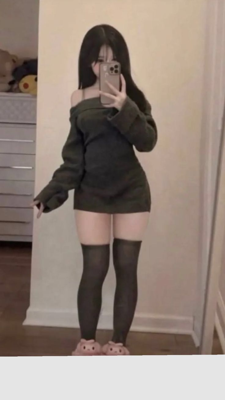 Woman in an off-shoulder top and thigh-high socks taking a mirror selfie