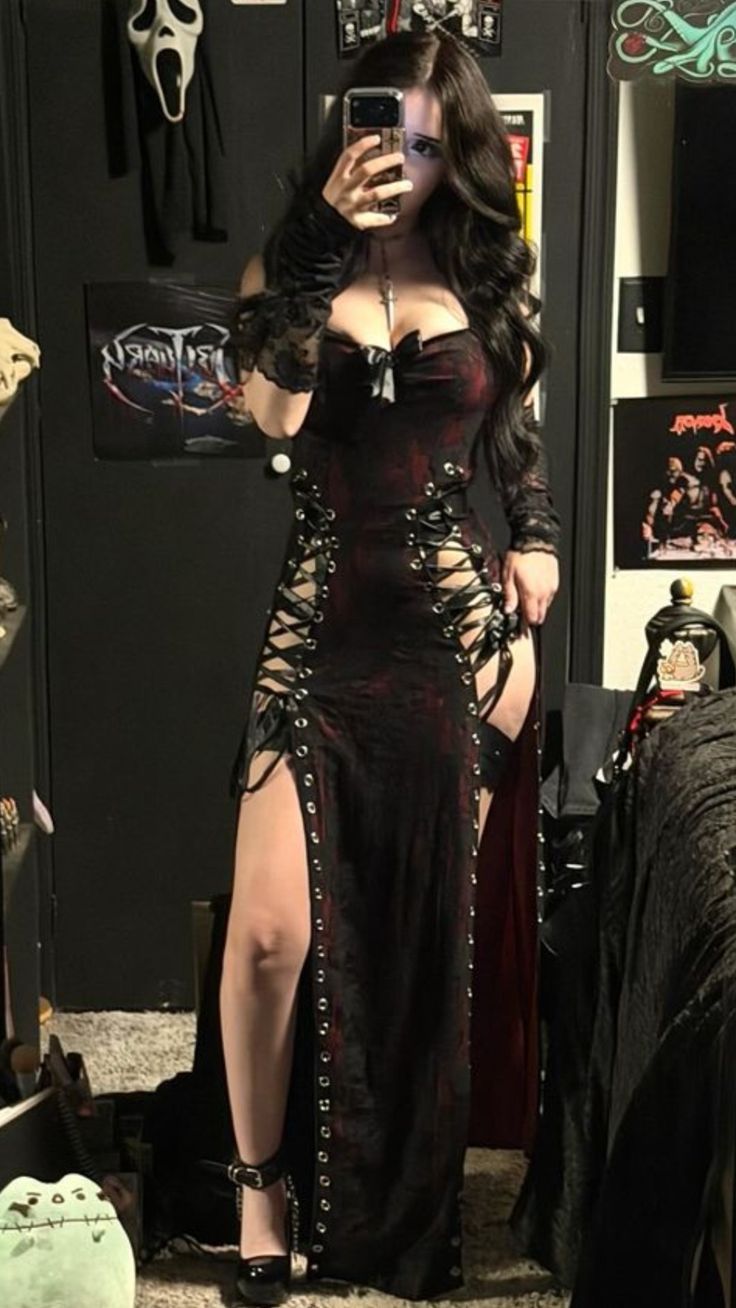 Woman in a gothic dress with lace-up sides and long dark hair taking a mirror selfie