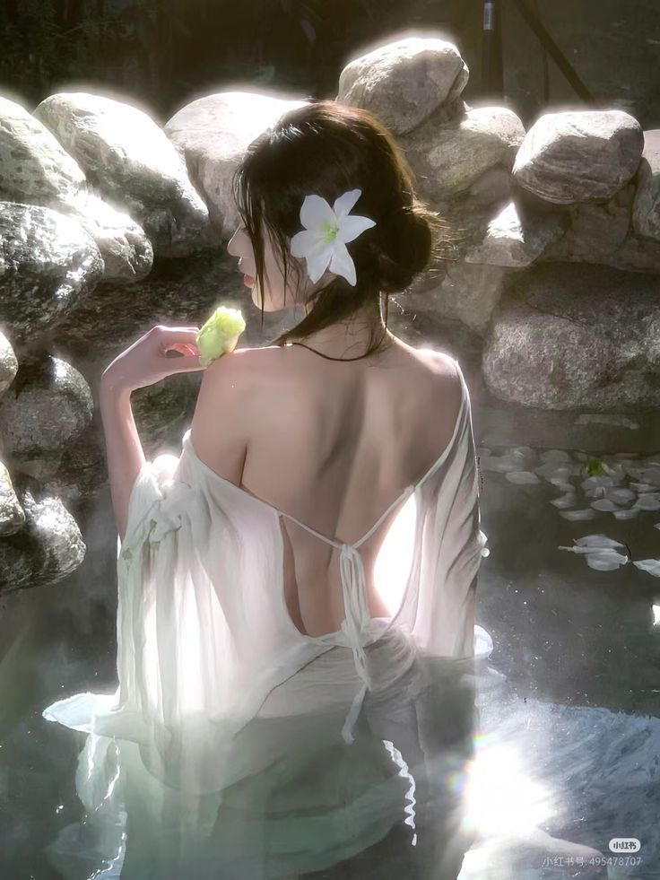 Woman in a white dress with an exposed back in water with soft lighting