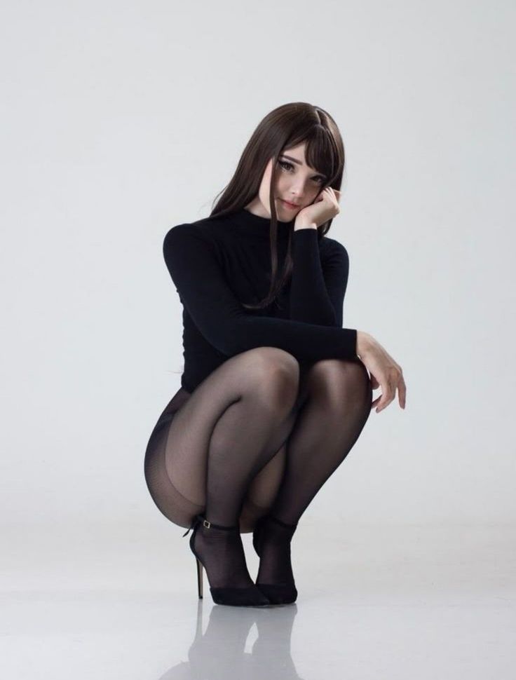 Woman in black tights and high heels squatting in a studio
