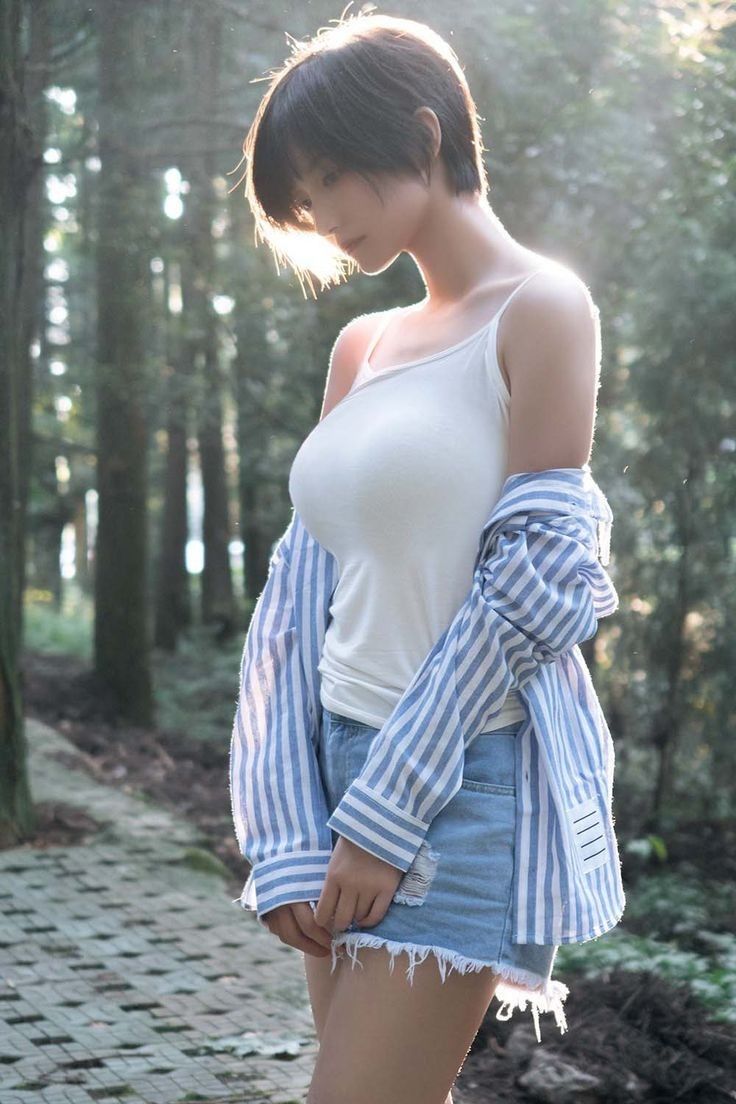 Woman with short hair in a white tank top and denim shorts in a forest