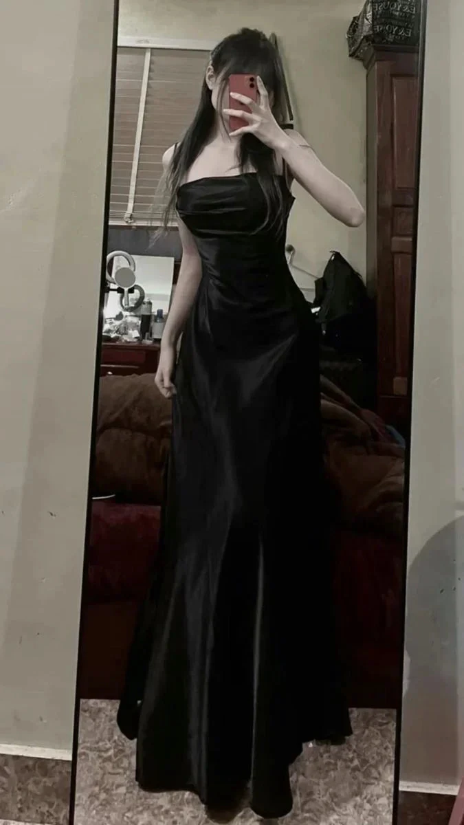 Person in a black dress taking a mirror selfie indoors