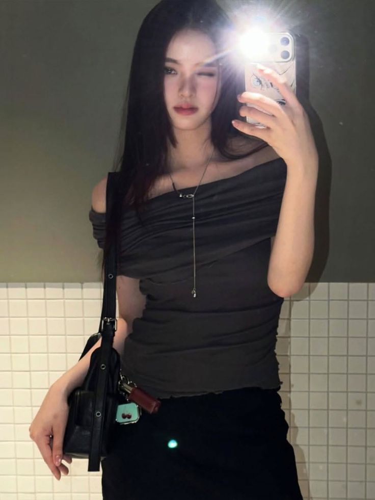 Woman with long dark hair taking a mirror selfie with flash