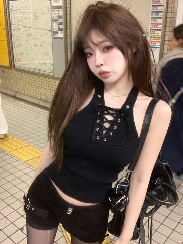 Woman in a black top and shorts posing in a subway station