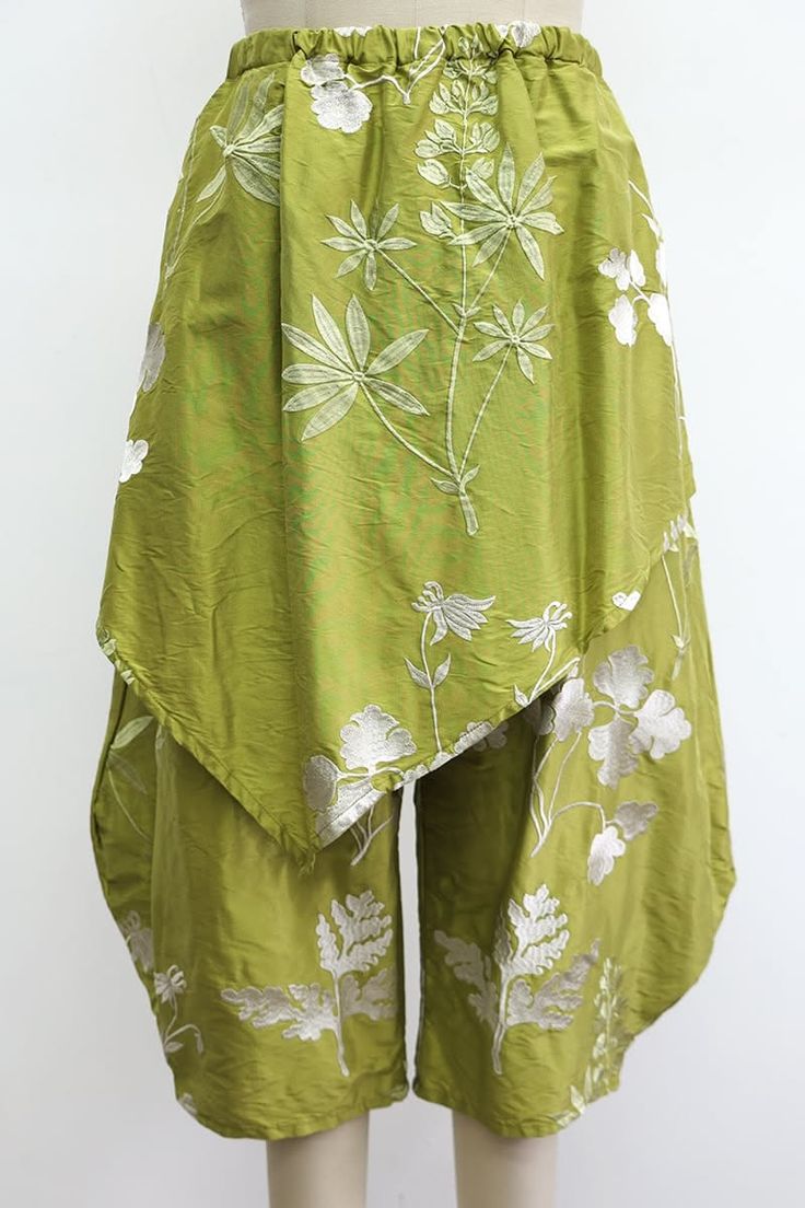 Green wide-leg pants with white floral embroidery and an asymmetrical overlay