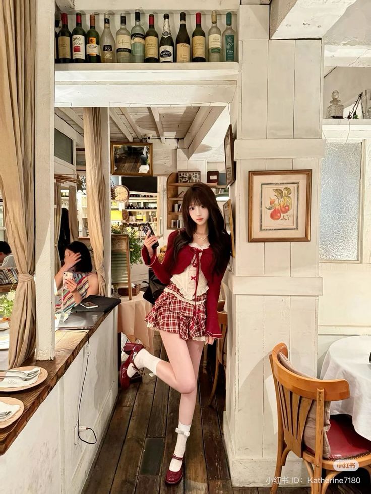 Woman in a red cardigan and plaid skirt posing in a restaurant