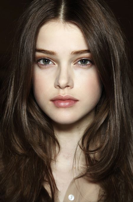 Close-up portrait of a woman with long brown hair and green eyes