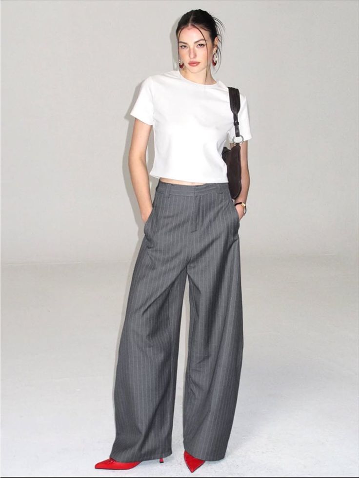 Woman in a white t-shirt and pinstripe pants with red heels in a studio