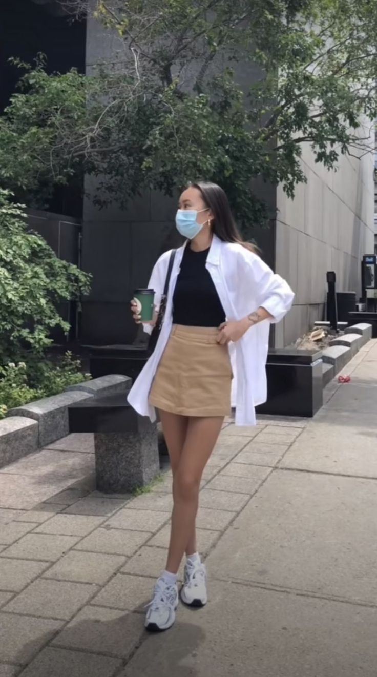Woman in a white shirt, black top, and mini skirt walking outdoors