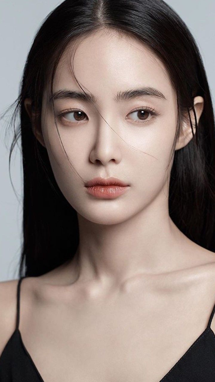 Woman with long black hair wearing a black top, looking to the side