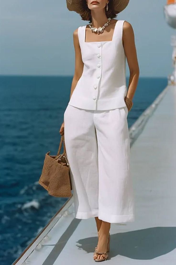 Woman in a white outfit and straw hat on a boat deck with ocean view