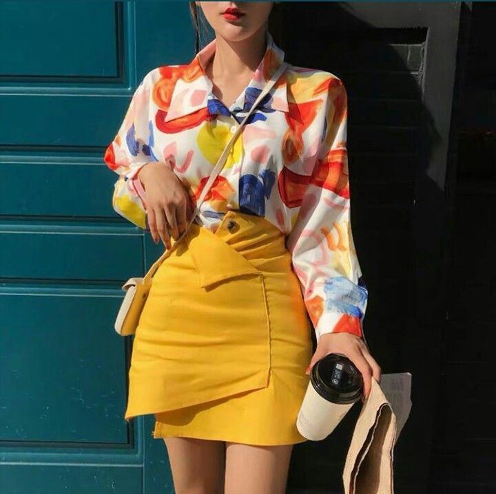 Person in a colorful shirt and yellow mini skirt holding a coffee cup