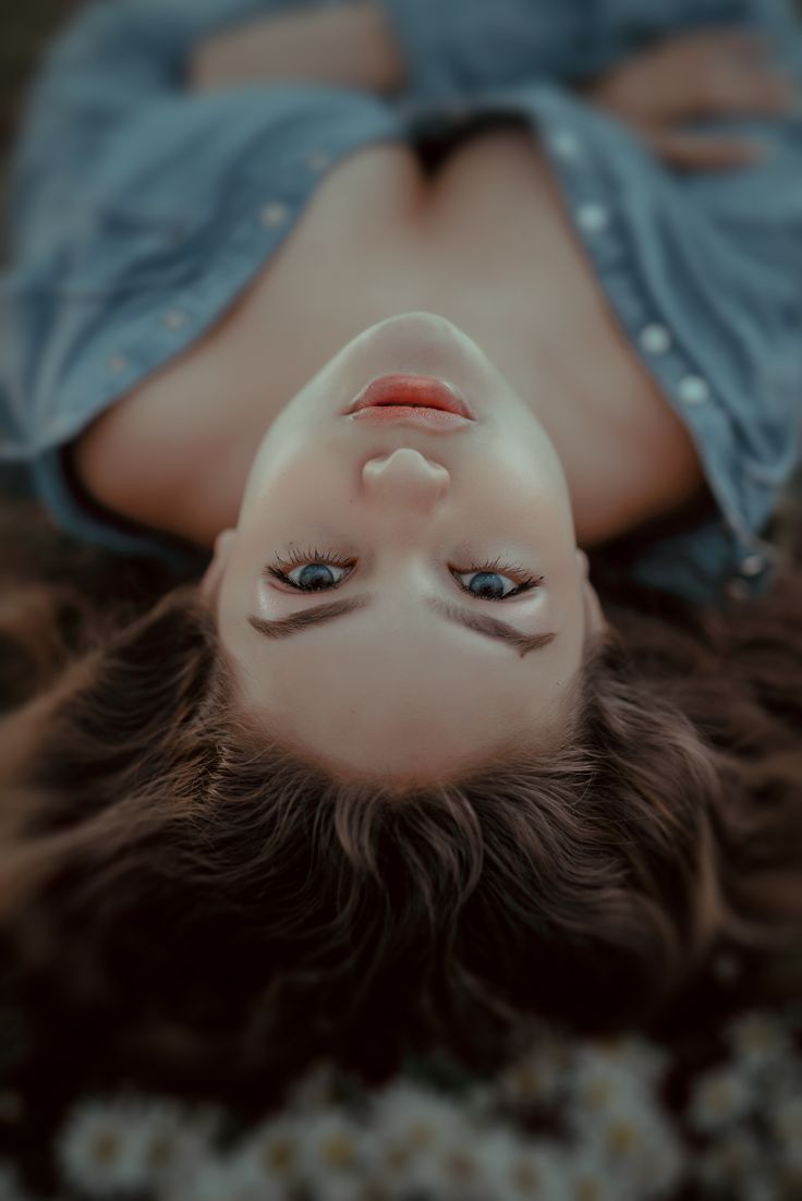 Woman with blue eyes and long hair lying down, wearing an open denim shirt