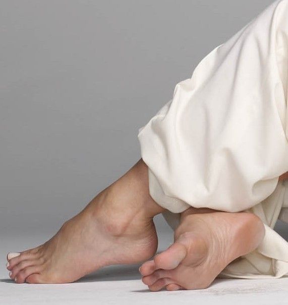 Bare feet with white toenails and white pants in a studio shot