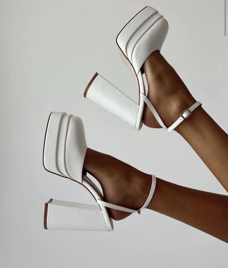 Two feet wearing white platform block heel shoes with ankle straps