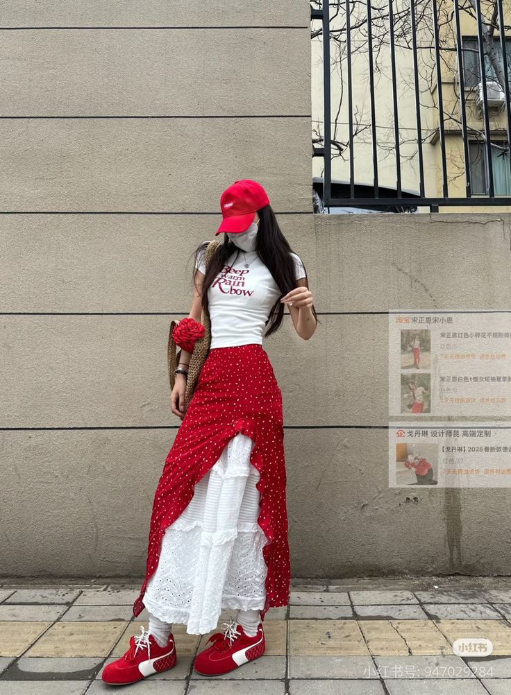 Woman in a red skirt and white top with a red cap standing on a street