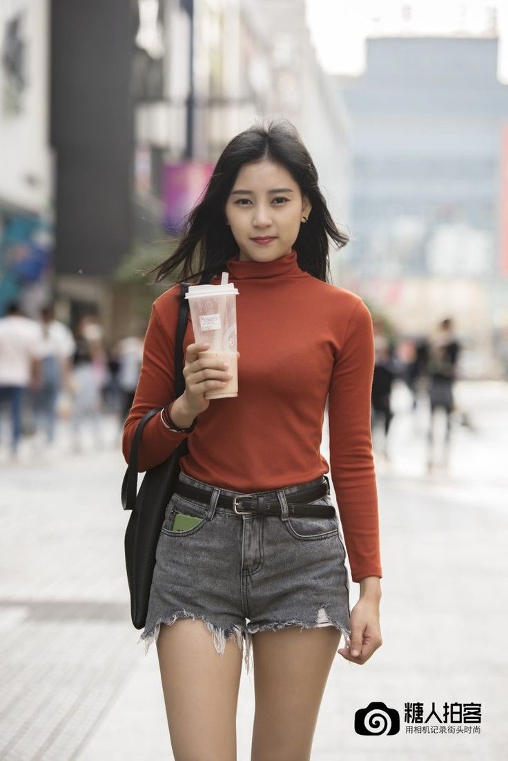 Woman in a red turtleneck and denim shorts walking on a street