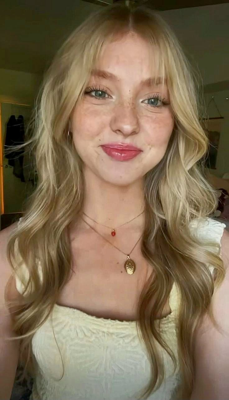 Blonde woman with freckles and long hair wearing necklaces