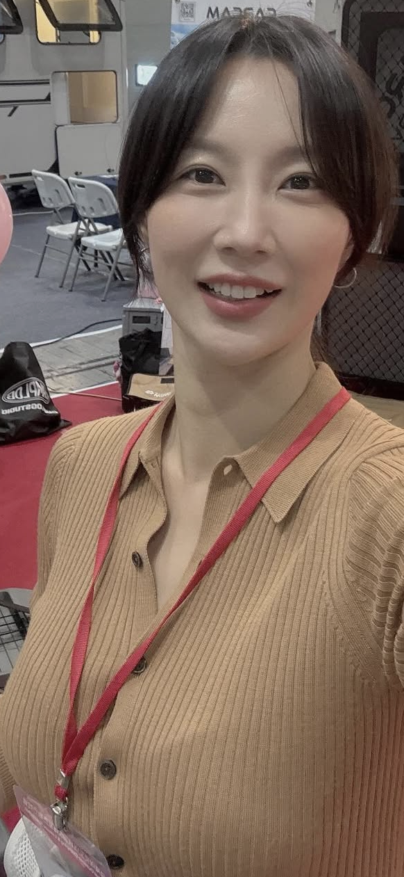 Woman with short hair and a red lanyard smiling indoors