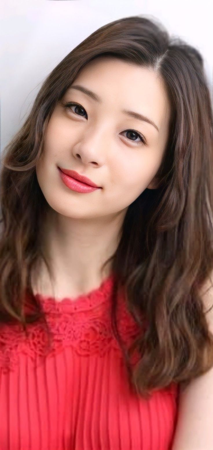 Woman with long wavy hair wearing a red dress with lace trim