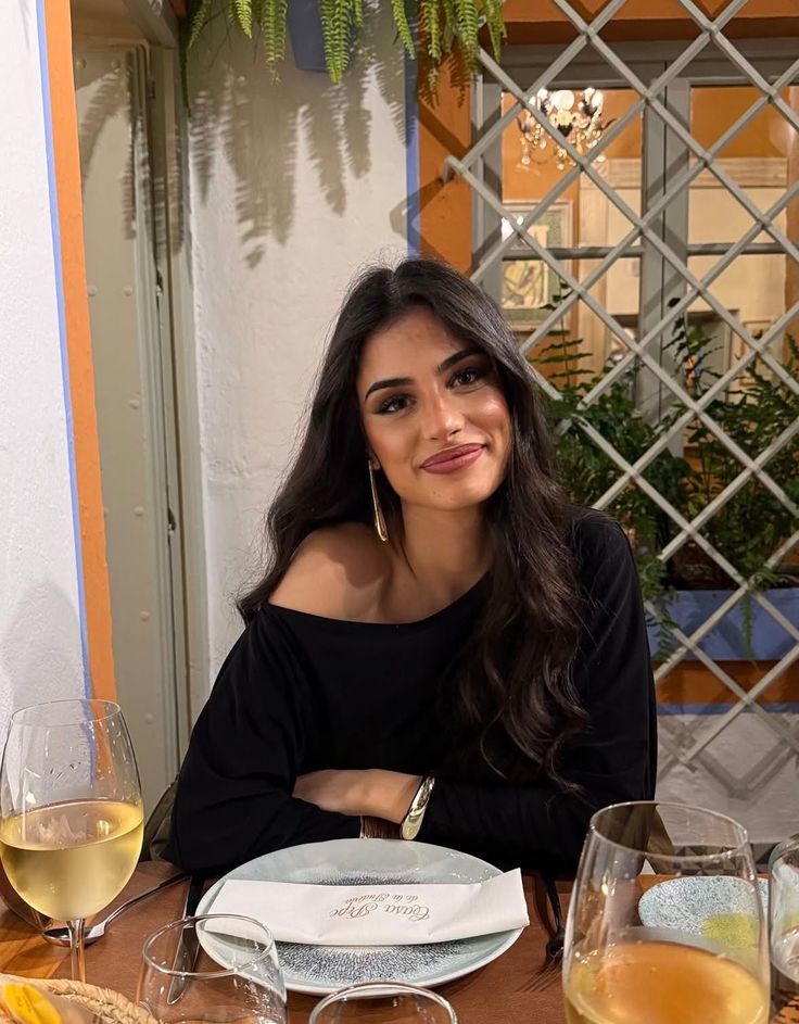 Woman with long dark hair wearing an off-shoulder top at a restaurant