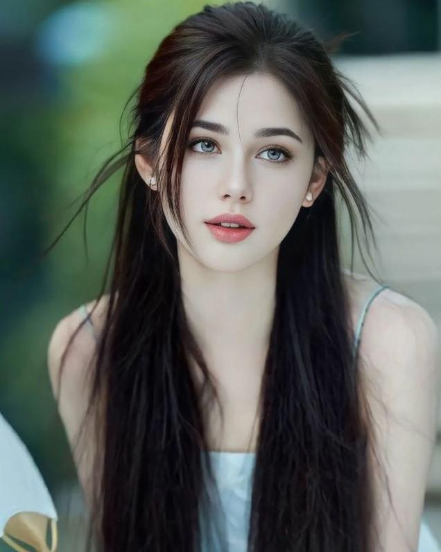 Woman with long dark hair and blue eyes wearing a light colored top