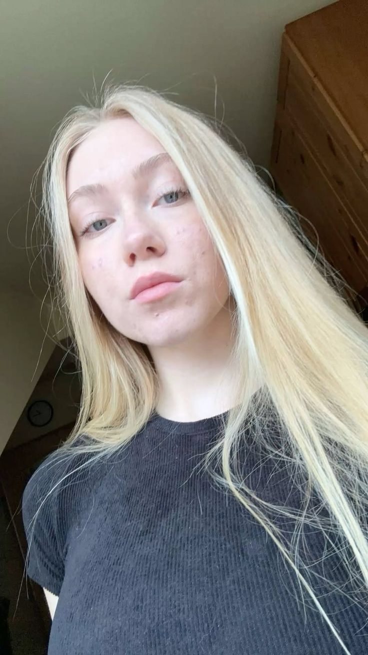 Young woman with long blonde hair wearing a black shirt indoors