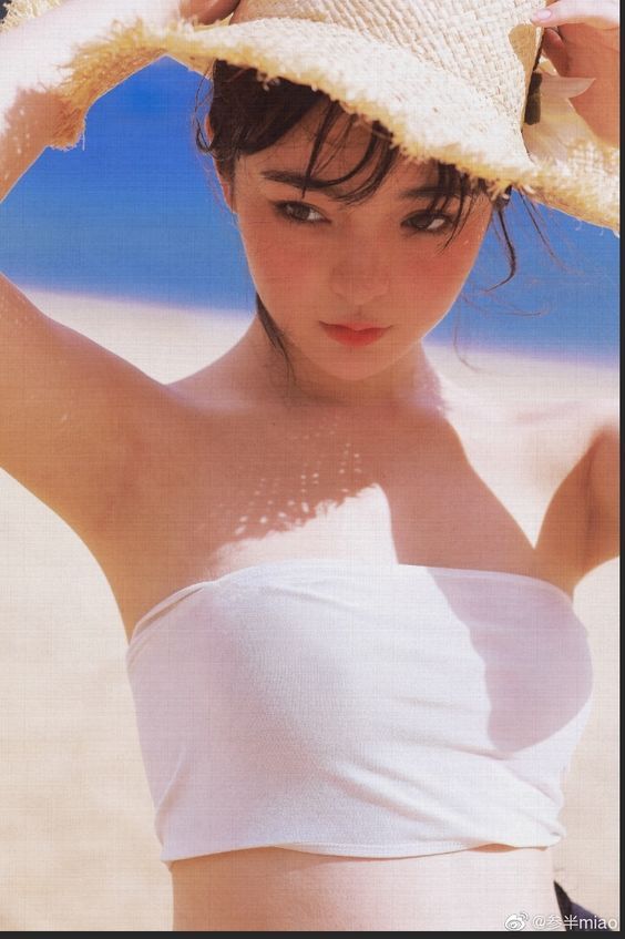 Woman in a straw hat and white top on a beach with soft lighting