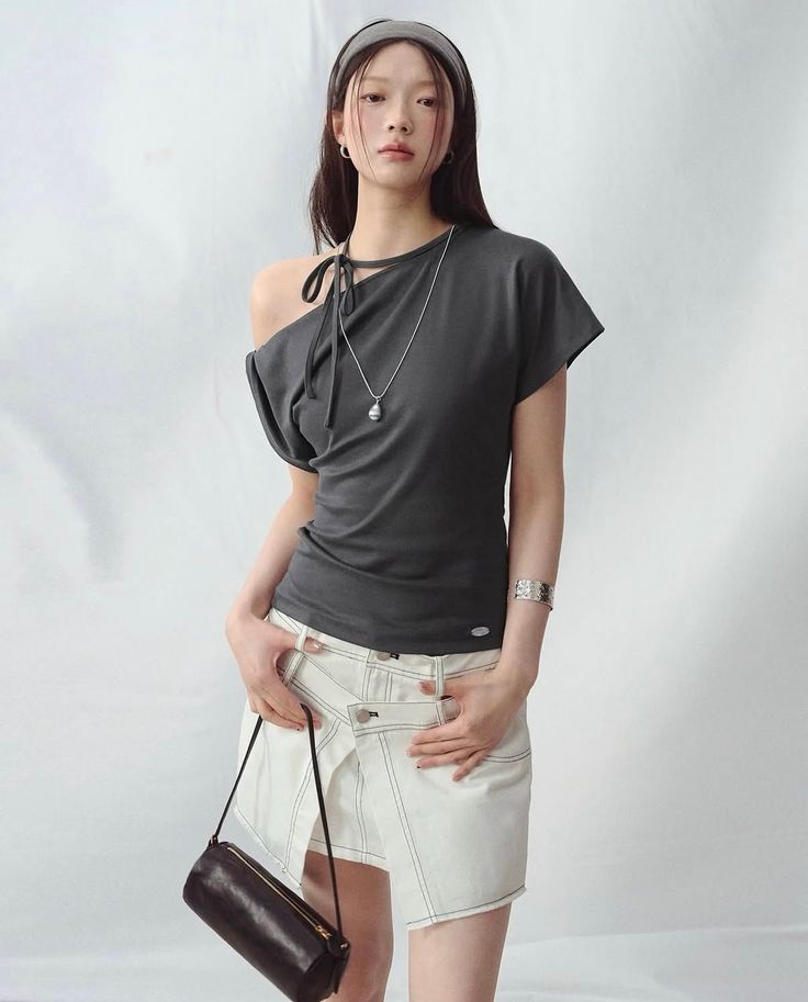 Woman with long hair wearing an off-shoulder top and white skirt in a studio