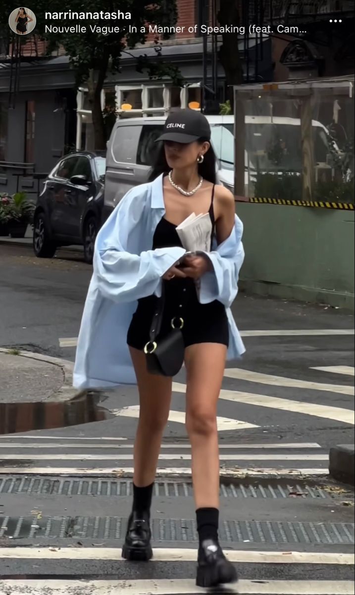 Woman in black shorts and a light blue shirt walking on a street