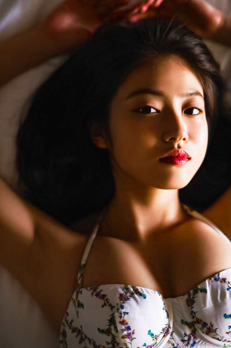 Woman with long dark hair and red lipstick wearing a floral top, looking at camera