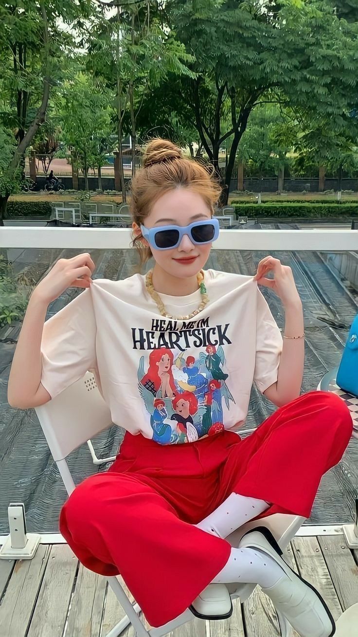 Woman in red pants and a graphic t-shirt wearing sunglasses outdoors