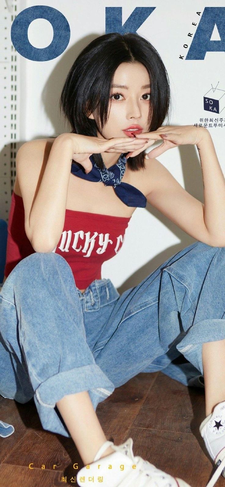 Woman with short black hair wearing a red tube top and blue jeans