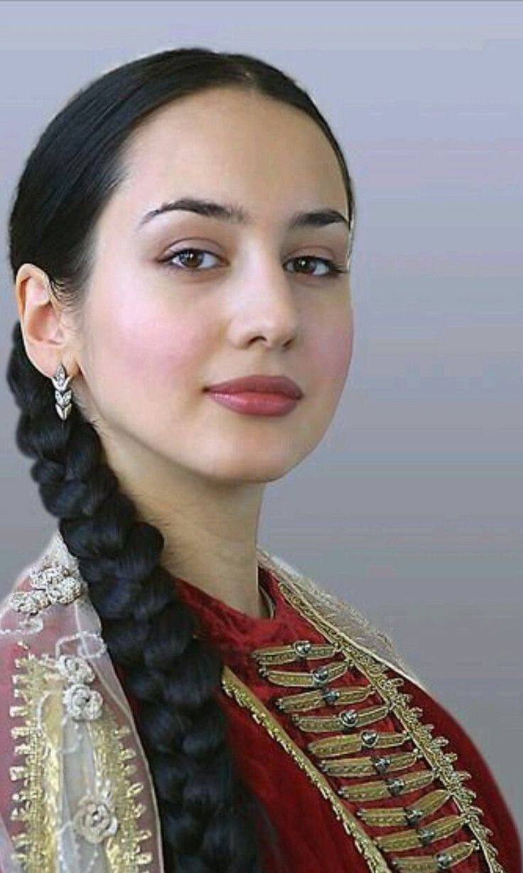 Woman in traditional red and gold clothing with a long black braid