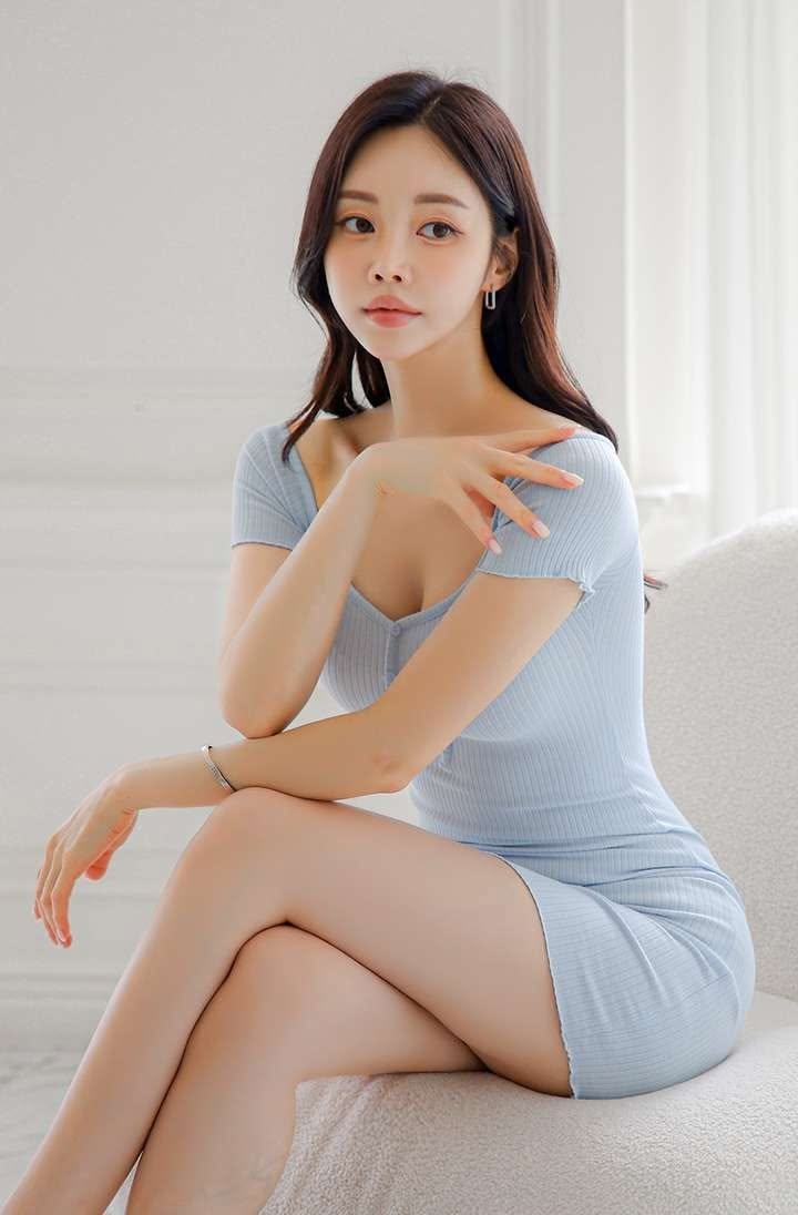 Woman in a light blue dress sitting indoors with soft lighting