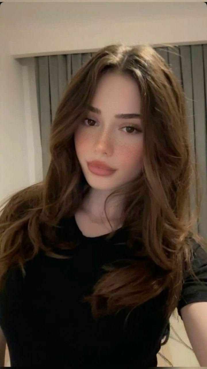 Woman with long brown hair and freckles wearing a black shirt indoors