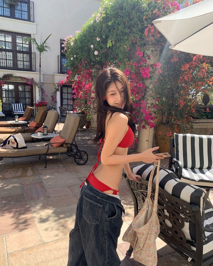 Woman in a red bikini top and loose jeans on an outdoor patio