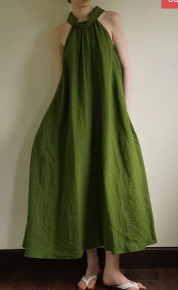 Person in a loose green halter neck dress standing indoors