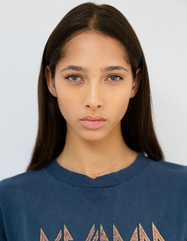 Woman with long dark hair and a blue t-shirt against a white background