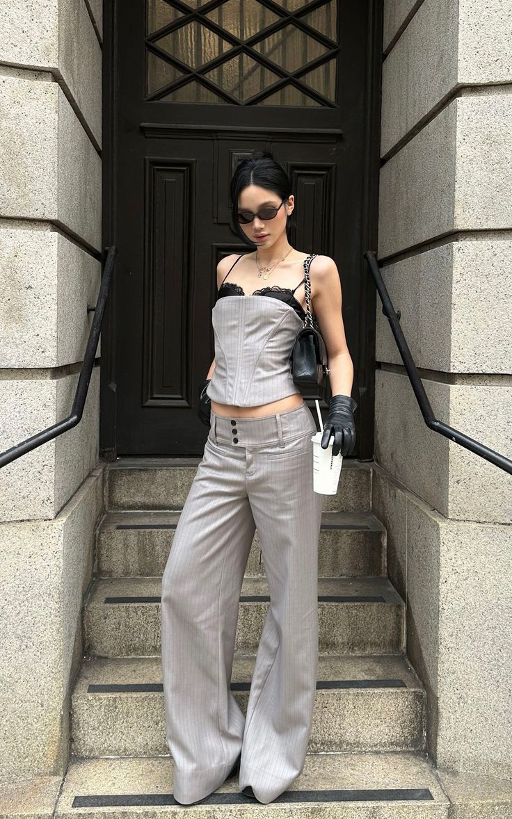 Woman in a corset top and pinstripe pants standing on stone steps