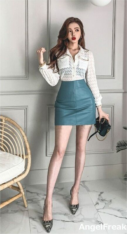Woman in a white blouse and blue mini skirt posing indoors