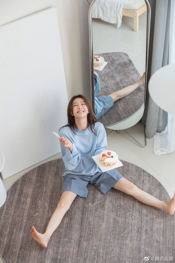 Woman in a striped shirt and shorts sitting on a rug with a cake