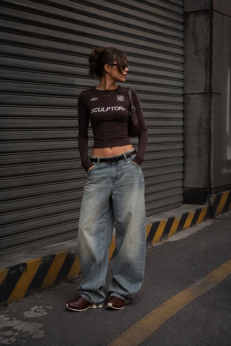 Woman in a cropped top and baggy jeans standing on a street