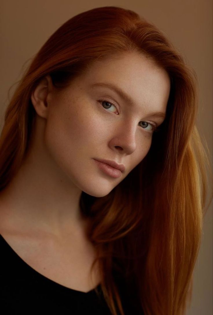 Close-up portrait of a woman with long red hair and freckles
