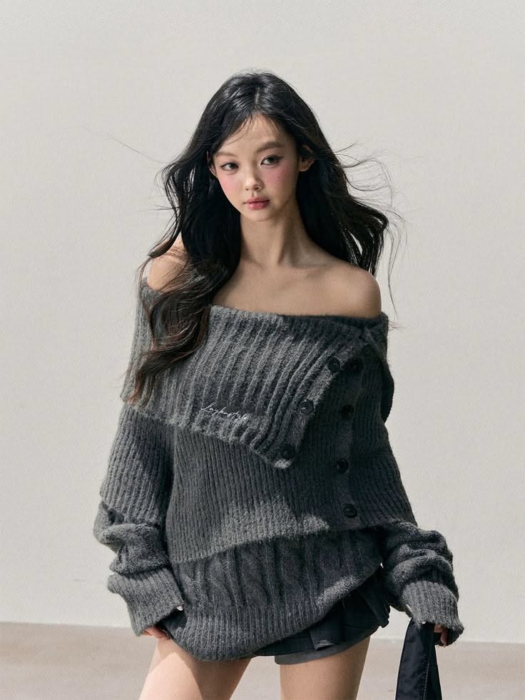 Woman with long dark hair wearing an off-shoulder dark grey sweater