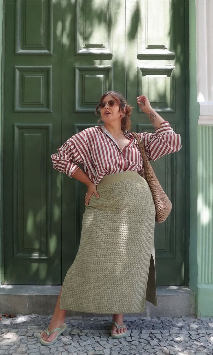 Woman in a striped shirt and long skirt posing in front of a green door