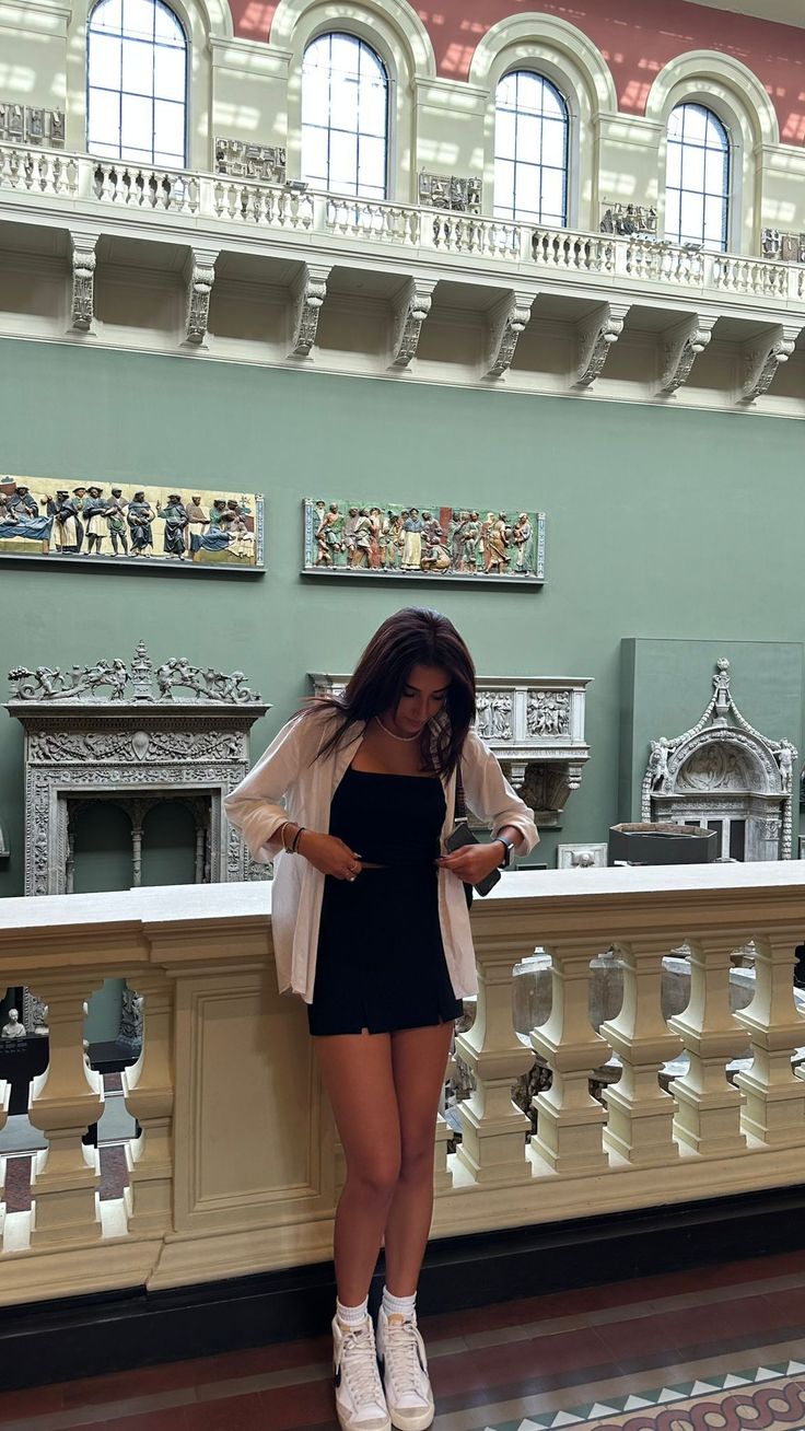 Woman in a black dress and white shirt standing in a museum
