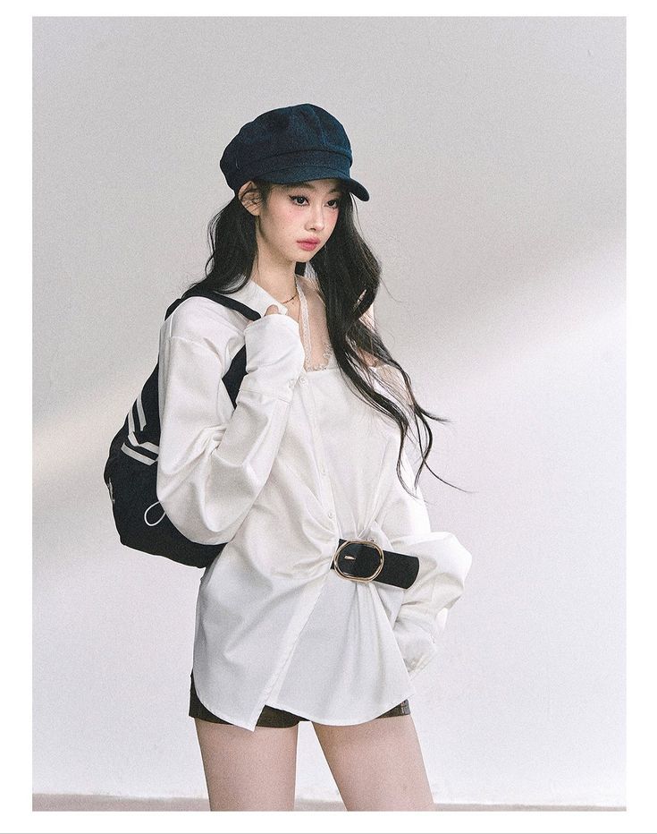 Woman with long dark hair wearing a white shirt and black cap with a backpack