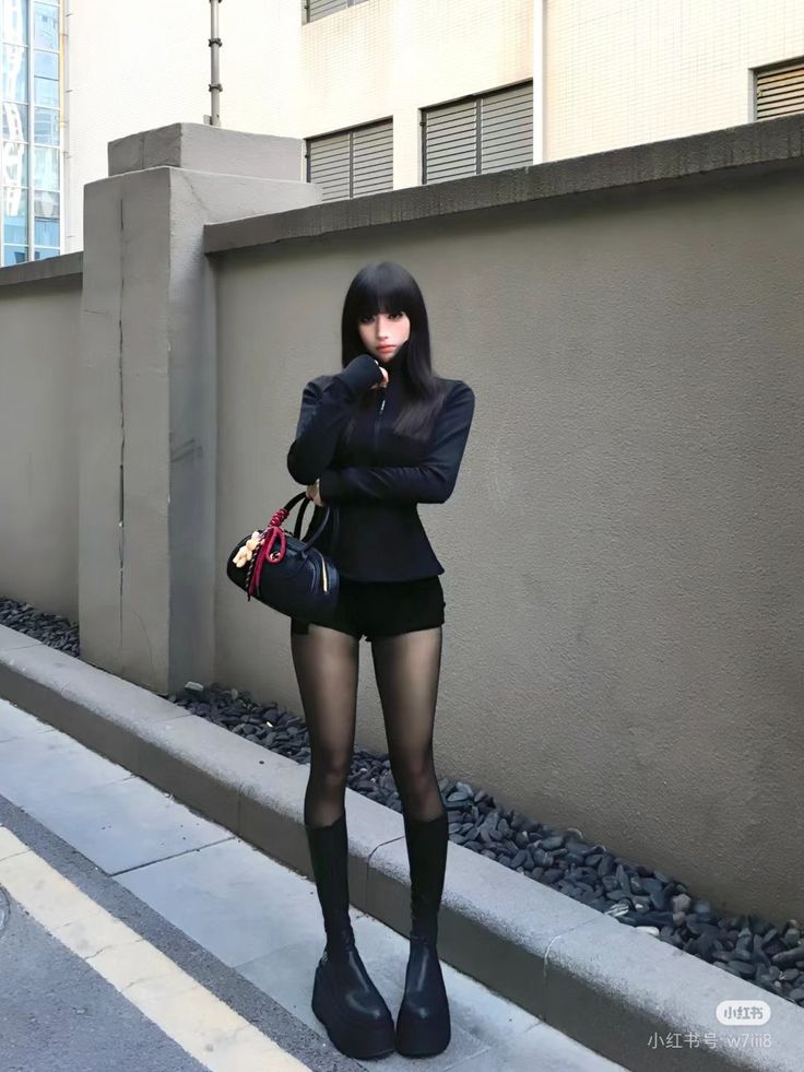 Woman with long black hair wearing a black top, shorts, and platform boots outdoors