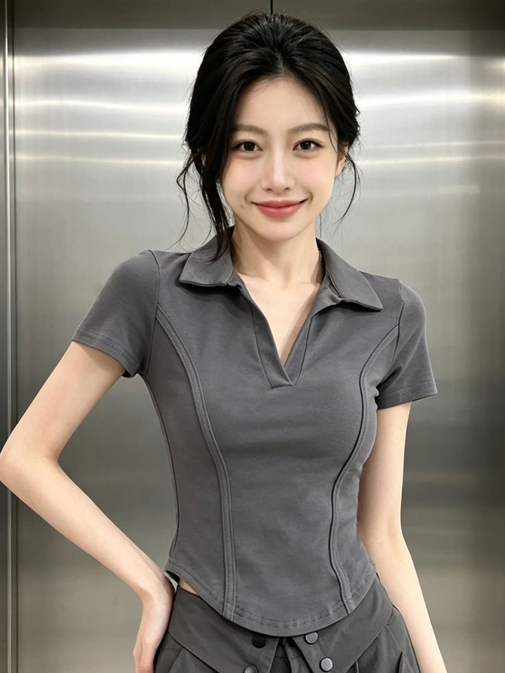 Woman with dark hair wearing a grey polo shirt, smiling at the camera